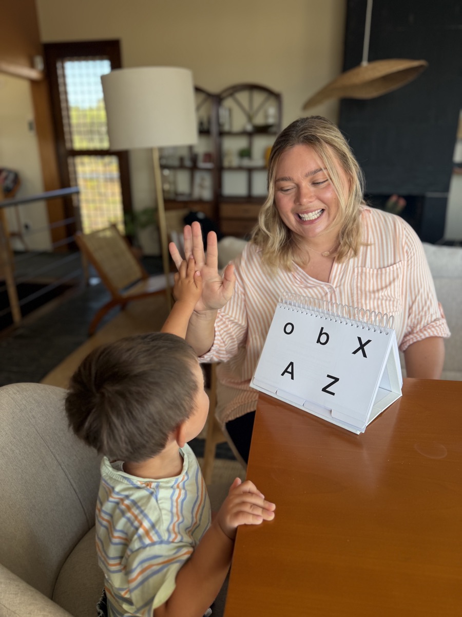 Aemelia Jackson high-fiving a young client during a speech therapy session at Clementine Speech Therapy in St. Petersburg, FL